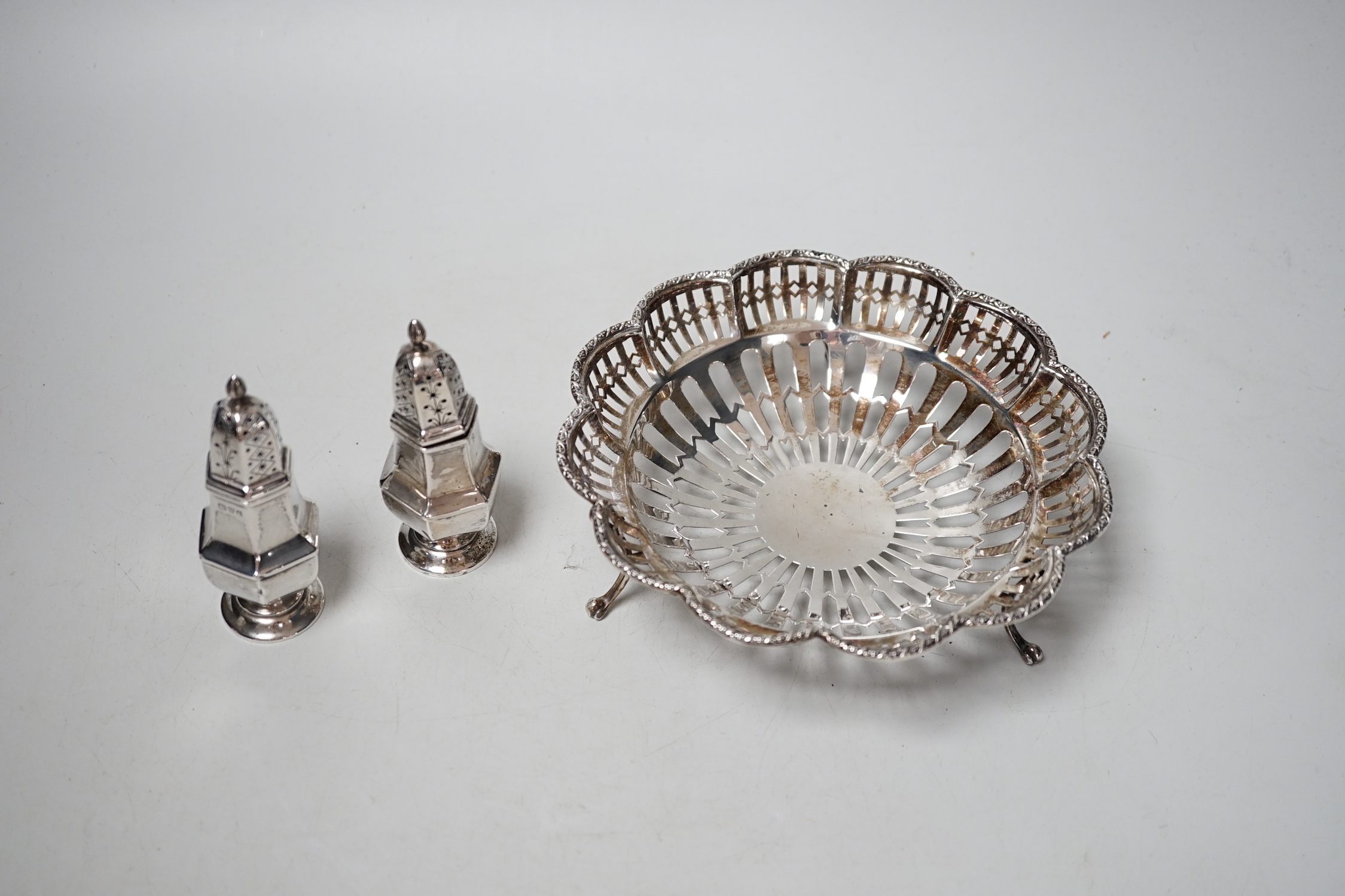 A George V pierced silver dish, Birmingham, 1912, 15.8cm and a pair of silver peppers, 5.9oz.